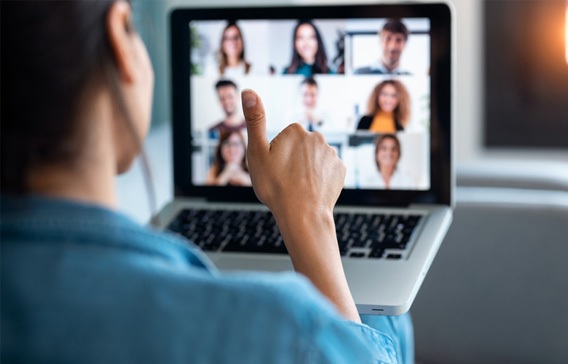 Homem de costa acena de forma positiva para uma tela do computador com uma reunião online