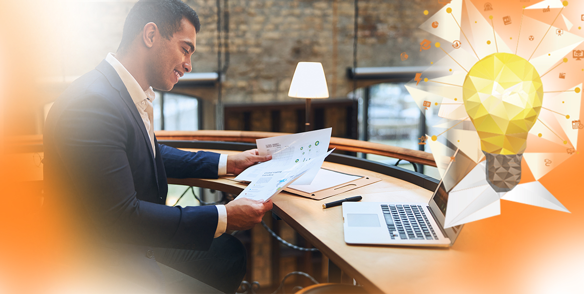 Homem sentado em frente ao notebook analisando documentos