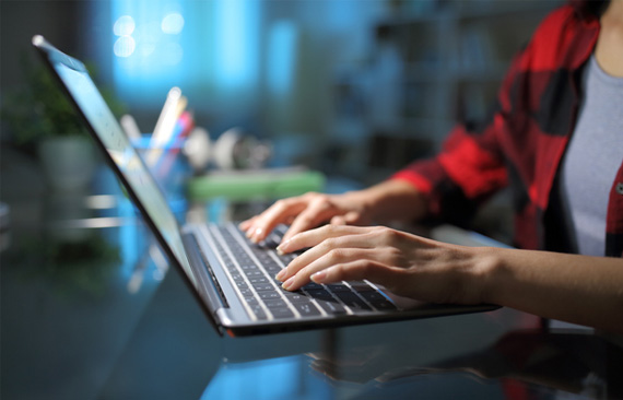 Imagem mostra a lateral direita de uma mulher que está usando um notebook