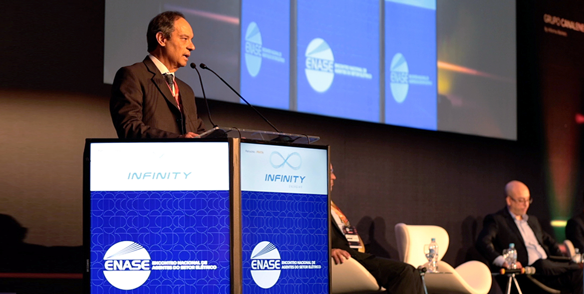 A imagem mostra o presidente do Conselho de Administração da CCEE, Rui Altieri, no palco do ENASE 2022. Ele é um homem branco e calvo de meia idade e veste um terno cinza.