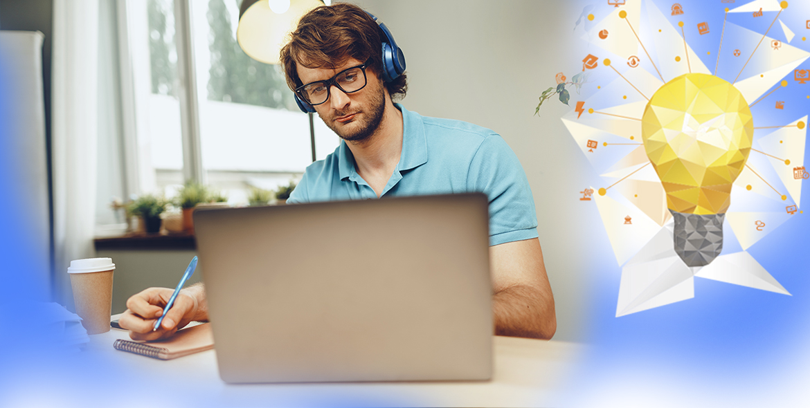 Foto de um homem branco e de cabelos ruivos em frente a um notebook. Ele usa fones de ouvido e veste uma camisa azul.