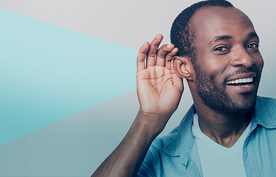 A imagem mostra um homem negro com suas mãos aos ouvidos, como se quisesse ouvir uma conversa ao longe