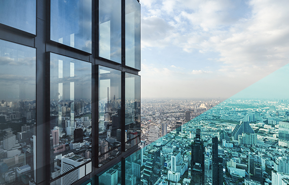 Fotografia do horizonte de uma grande cidade, recortada pelo perfil de um prédio espelhado