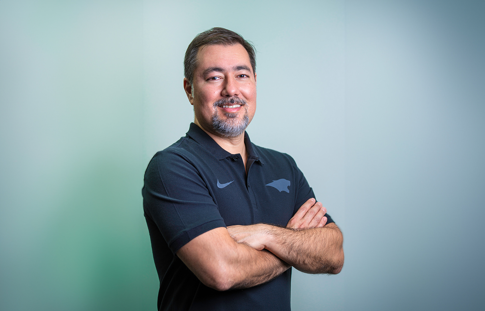 Foto do Gerente Executivo Tiago Hayashida. Ele é um homem asiático e veste uma camiseta polo azul petróleo.