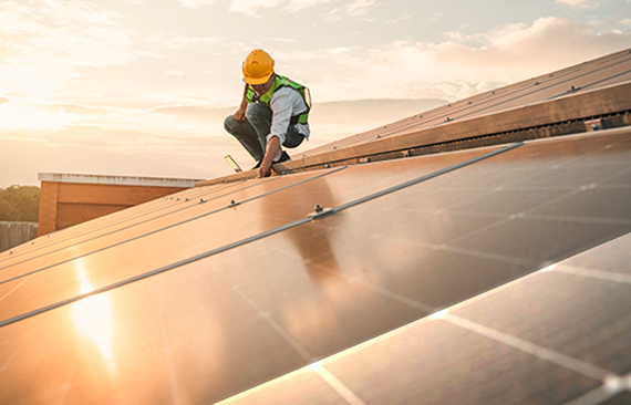 Imagem mostra um técnico sobre placas de geração de energia solares 