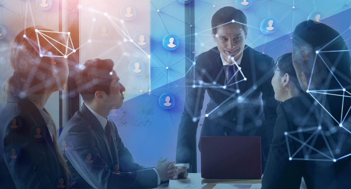 A imagem mostra um grupo de executivos reunidos em torno de uma mesa, em um cenário de escritório