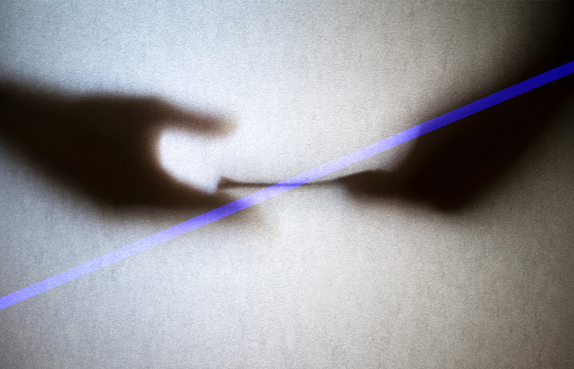 A imagem mostra as sombras de duas mãos que trocam documentos entre si. à frente uma linha diagonal corta o movimento.